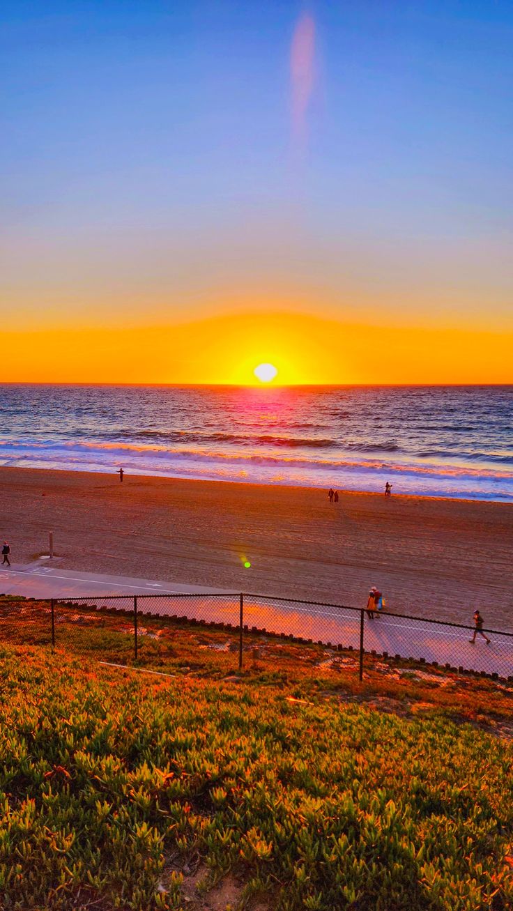 the sun is setting over the ocean and beach