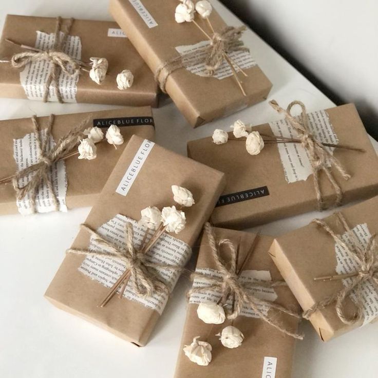 six wrapped presents are sitting on the table together, tied with twine and paper