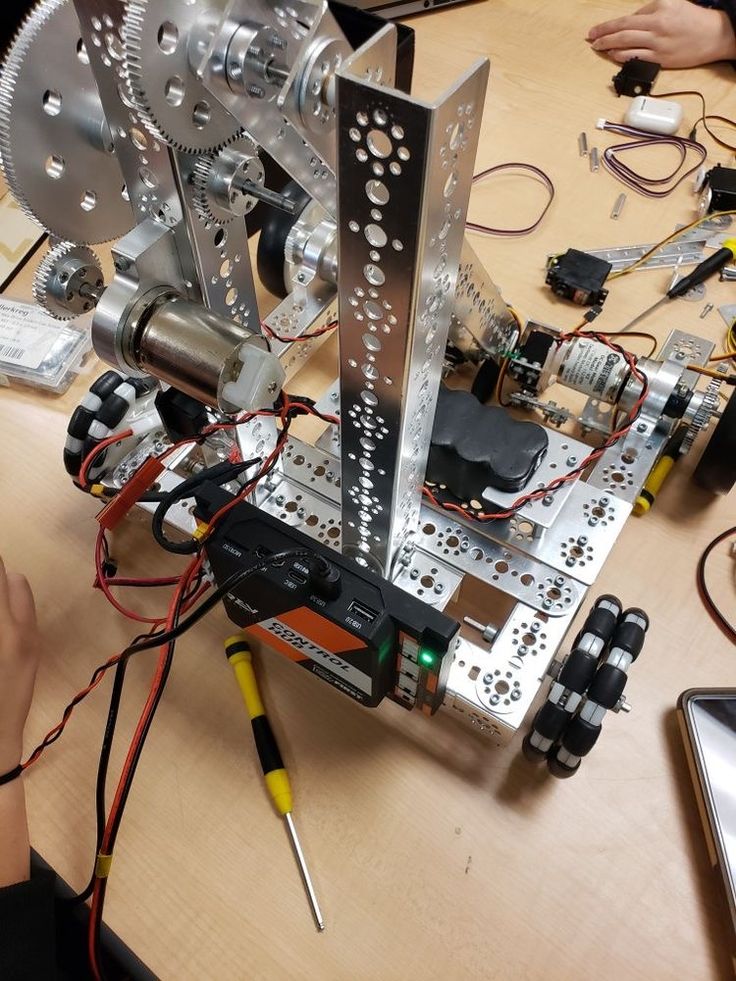 an assembled robot sitting on top of a wooden table next to wires and other electronics