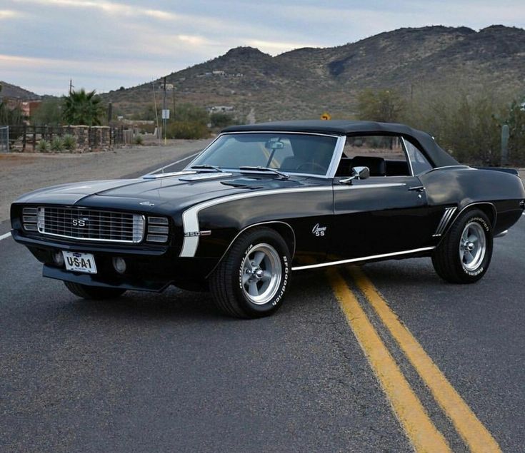 a black muscle car is parked on the side of the road