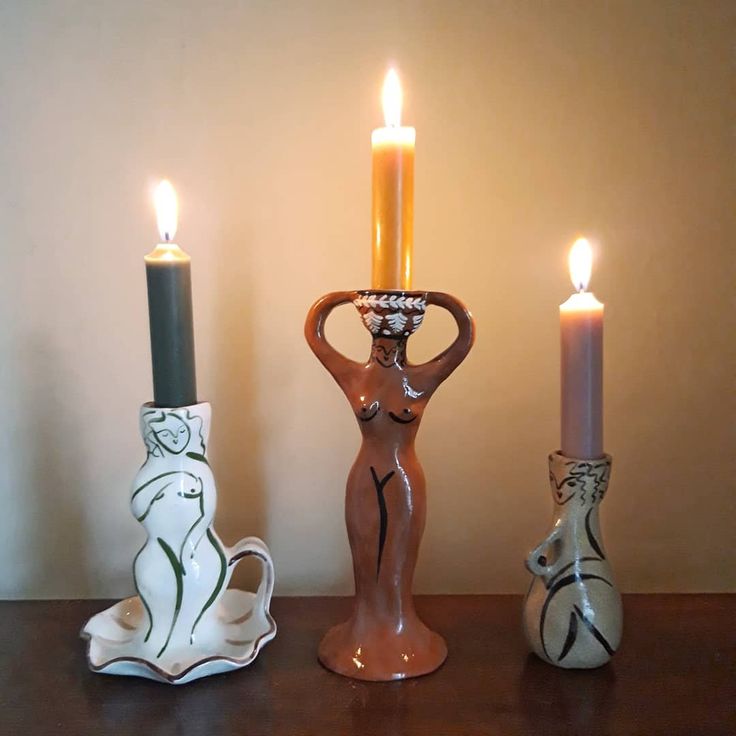 three candles sitting on top of a table next to vases and figurines