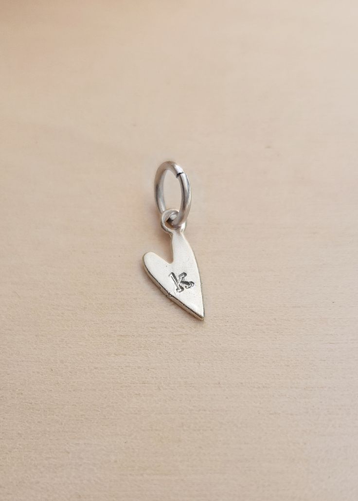 Add character and personalization to your jewelry with our Initial Heart Charm. Perfect for bracelets or necklaces, this charm adds a unique touch that reflects your individuality. Crafted with care and attention to detail, it's the perfect addition to any accessory collection. Size: 14mm x 7mm Available in gold plated over sterling silver, sterling silver, or rose gold plated over sterling silver. Ring Spacer, Hoop Charms, Name Rings, Layered Chains, Birthstone Ring, Bridal Gifts, Beaded Chain, Heart Charm, Layered Necklaces