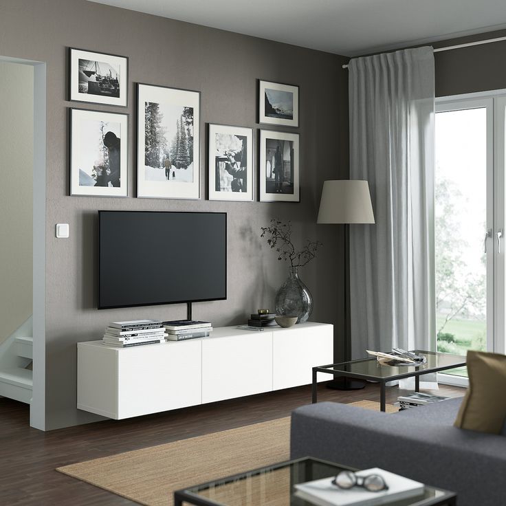 a living room with pictures on the wall and a television in front of a window