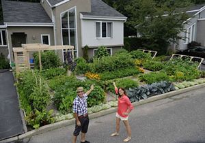 two people standing in the middle of a street with lots of plants and vegetables on it