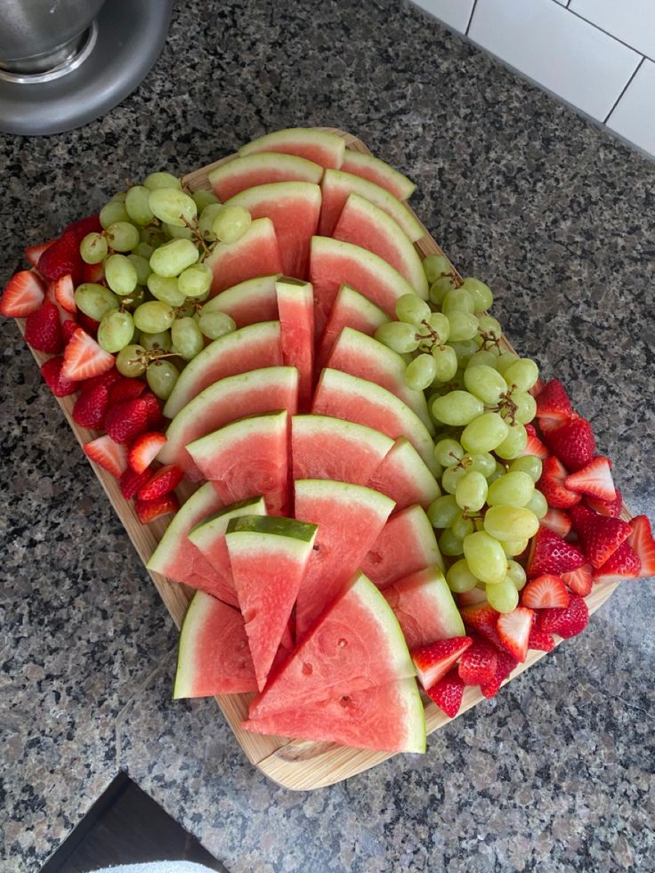 sliced up watermelon and grapes on a cutting board