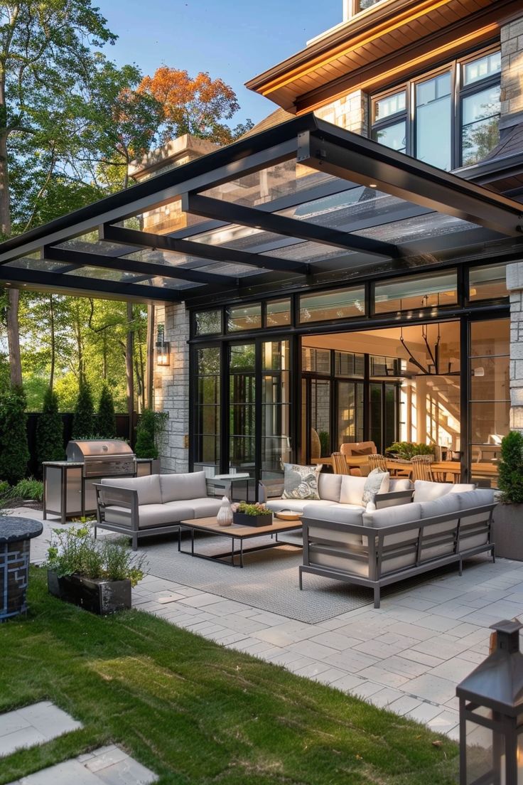 an outdoor living area with couches, tables and fire pit in front of a house