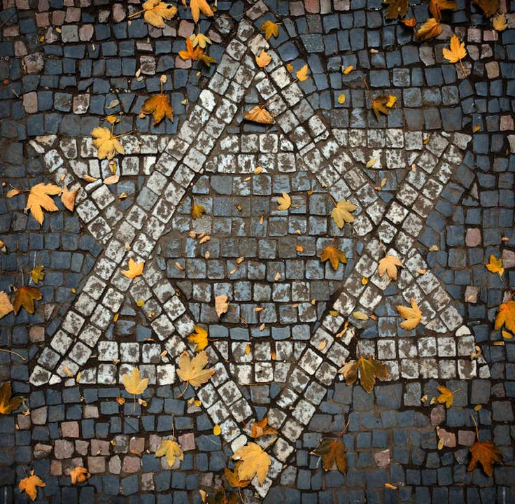 the star of david surrounded by leaves on a cobblestone street in autumn time