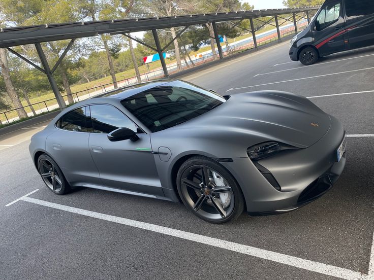 a silver sports car parked on the side of a road next to a black van