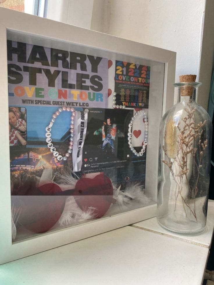 a glass bottle with some stuff in it sitting next to a poster and a heart