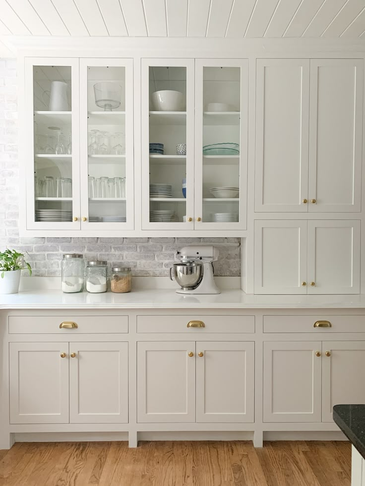 a kitchen with white cabinets and wood floors