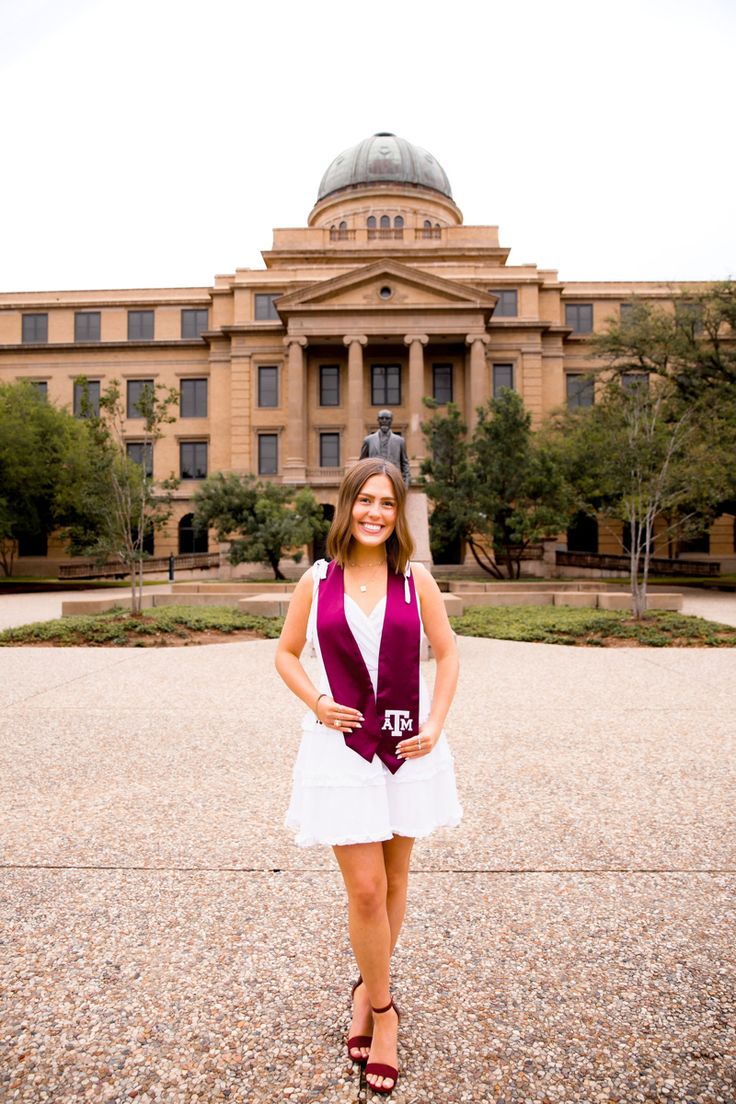 a woman standing in front of a large building wearing a purple and white scarf over her neck