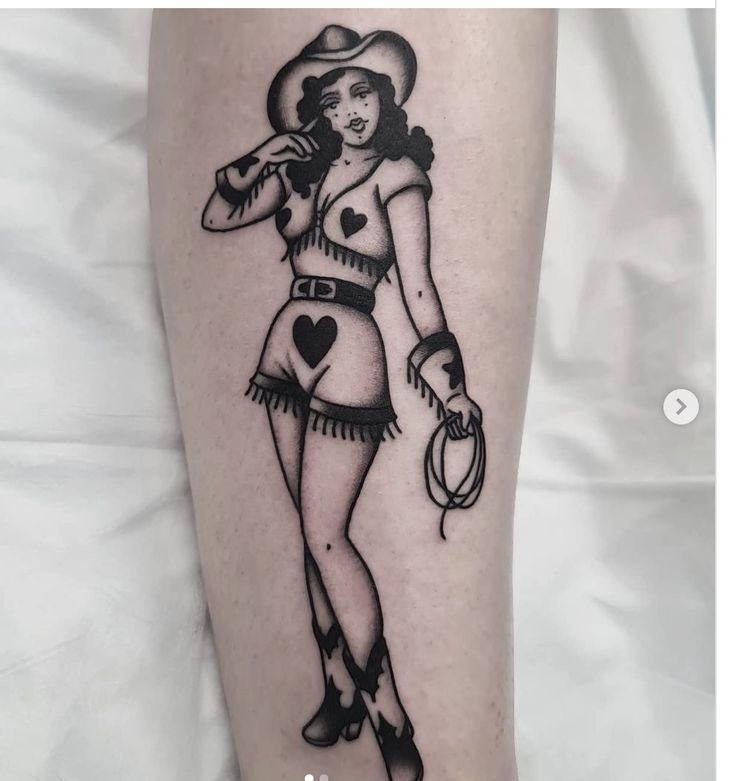 a woman with a cowboy hat and lasso tattoo on her leg is holding a lasso