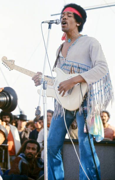 a man with a guitar sings into a microphone while people watch from the sidelines