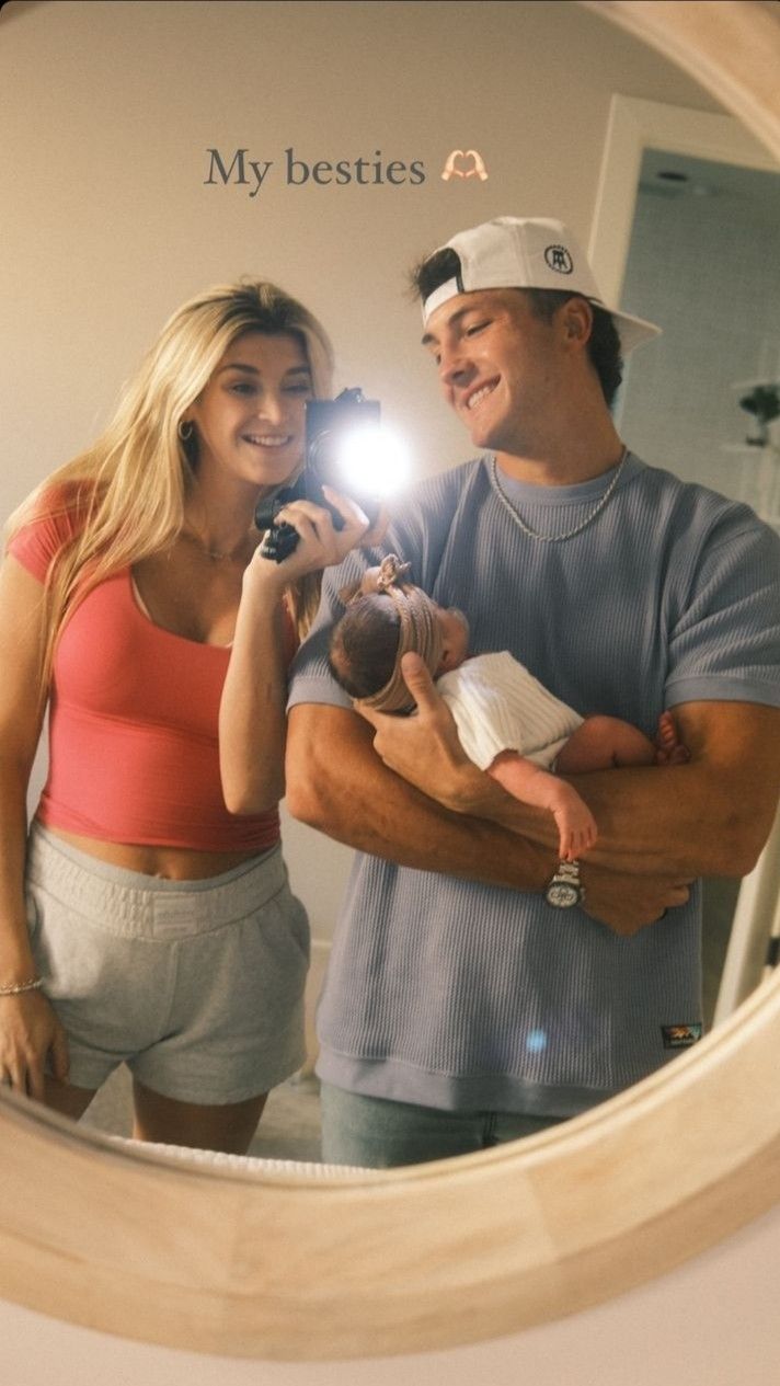 a man and woman holding a baby in front of a mirror that says my besties