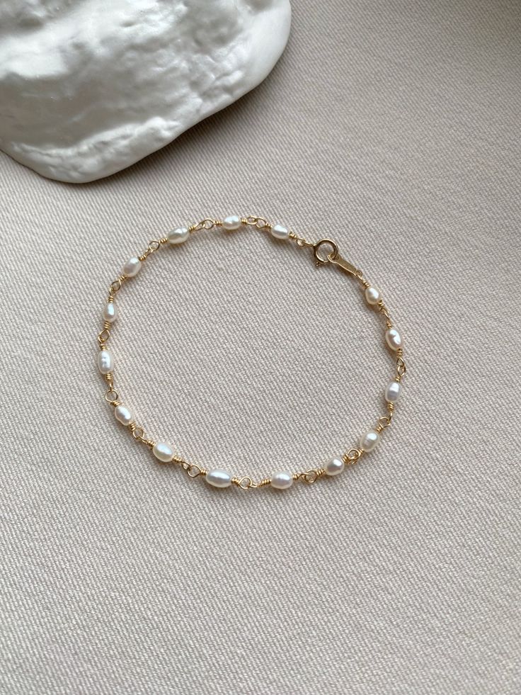 This Pearl Bracelet in durable and hypo-allergenic 14K Gold Filled is a celebration of simplicity and sophistication. The small pearls, resembling delicate grains of rice, add a charming touch to this beautiful piece. Crafted with care, it offers a refined and graceful look, perfect for those who appreciate the subtle charm of natural elements in their accessories. Elegant enough for special occasions yet understated for everyday wear, this pearl bracelet is a timeless companion. PRODUCT DETAILS Rice Pearl Bracelet Gold, Pearl And Gold Bracelet, Pearl Bracelet Aesthetic, Pearl Bracelet Stack, Dainty Pearl Bracelet, Permanent Bracelet, Gold Bracelet Wedding, Accessories Elegant, Pearl Bracelet Gold