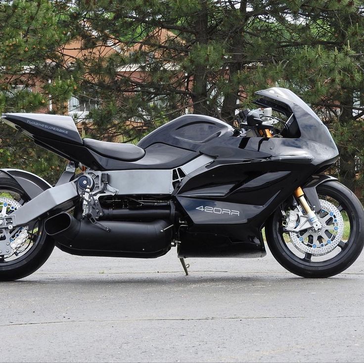 a black motorcycle parked in front of some trees