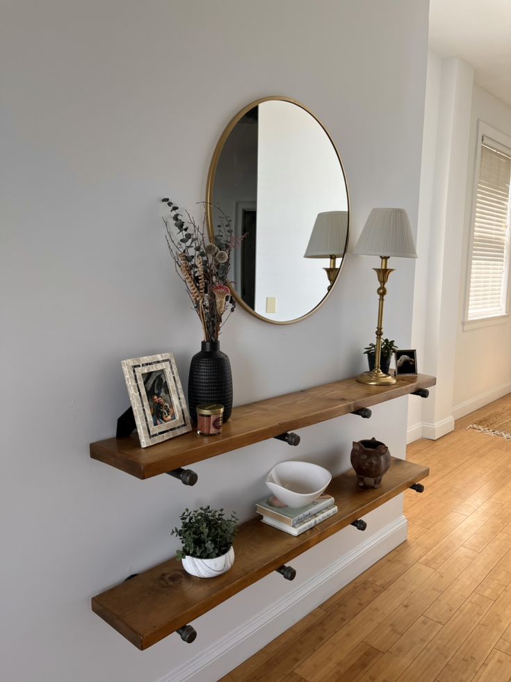 two wooden shelves with mirrors and vases on them in front of a white wall