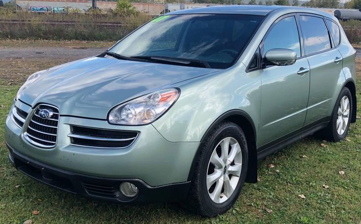 a green car parked on top of a grass covered field