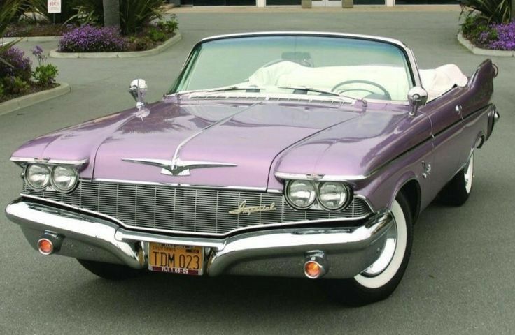 an old purple car is parked on the street