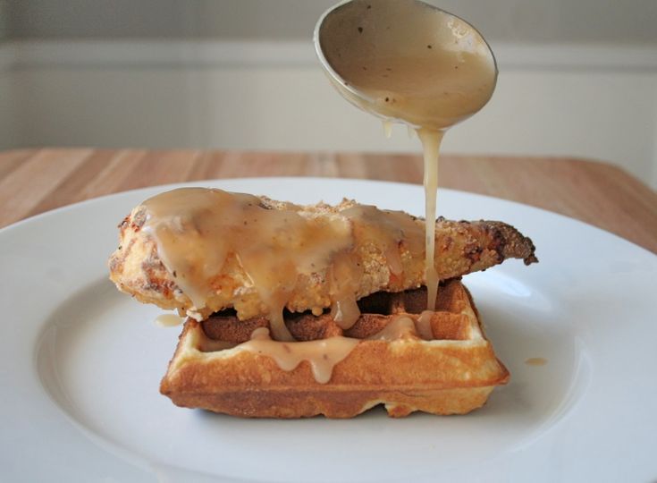 a chicken and waffle sandwich is being drizzled with gravy