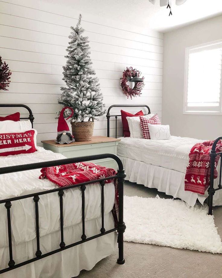 two beds in a room with christmas decorations on the wall and white walls, along with a small tree