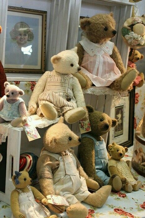 a group of teddy bears sitting on top of a table next to pictures and frames