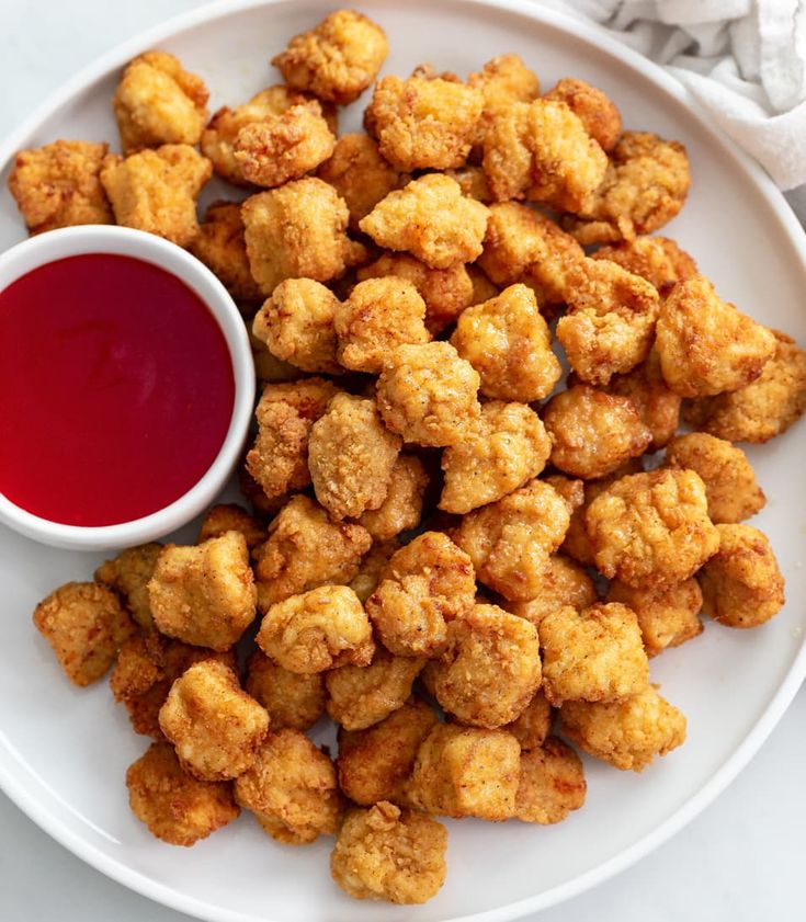 a white plate topped with tater tots next to a cup of ketchup