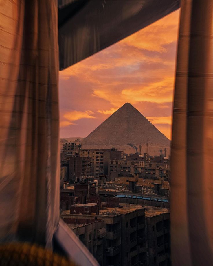 the view from inside a window looking out at an egyptian city with a pyramid in the distance