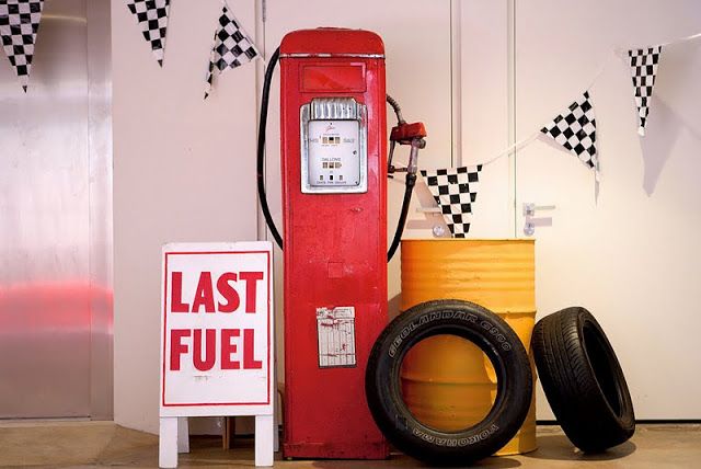 a red gas pump sitting next to two tires and a sign that says last fuel