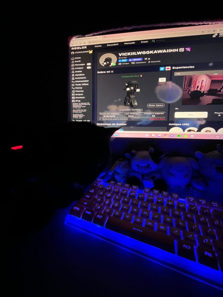 a laptop computer sitting on top of a desk next to a mouse and keyboard in the dark