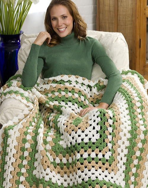 a woman sitting on a couch with a green and white blanket