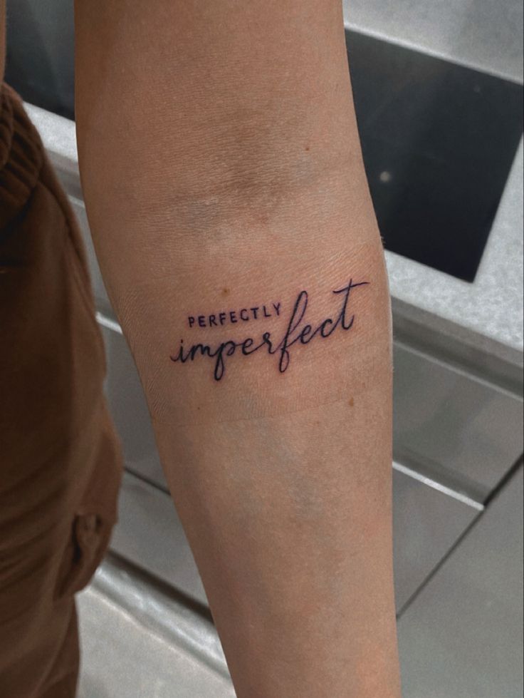 a person with a tattoo on their arm that says perfectly imperflet in cursive writing