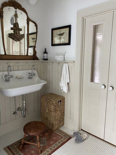 a white sink sitting under a mirror next to a wooden stool in a bath room