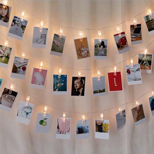 a string of lights is hanging from a wall with pictures on it and candles in the middle