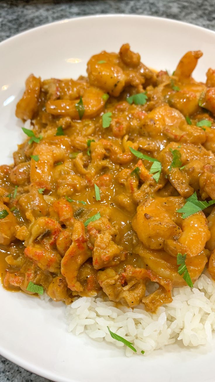 a white plate topped with rice and meat covered in gravy on top of a table