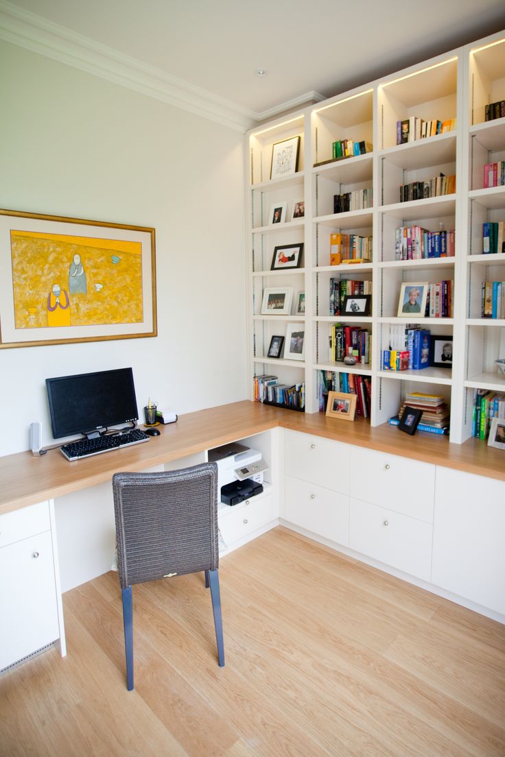 a computer desk sitting in front of a book shelf filled with books