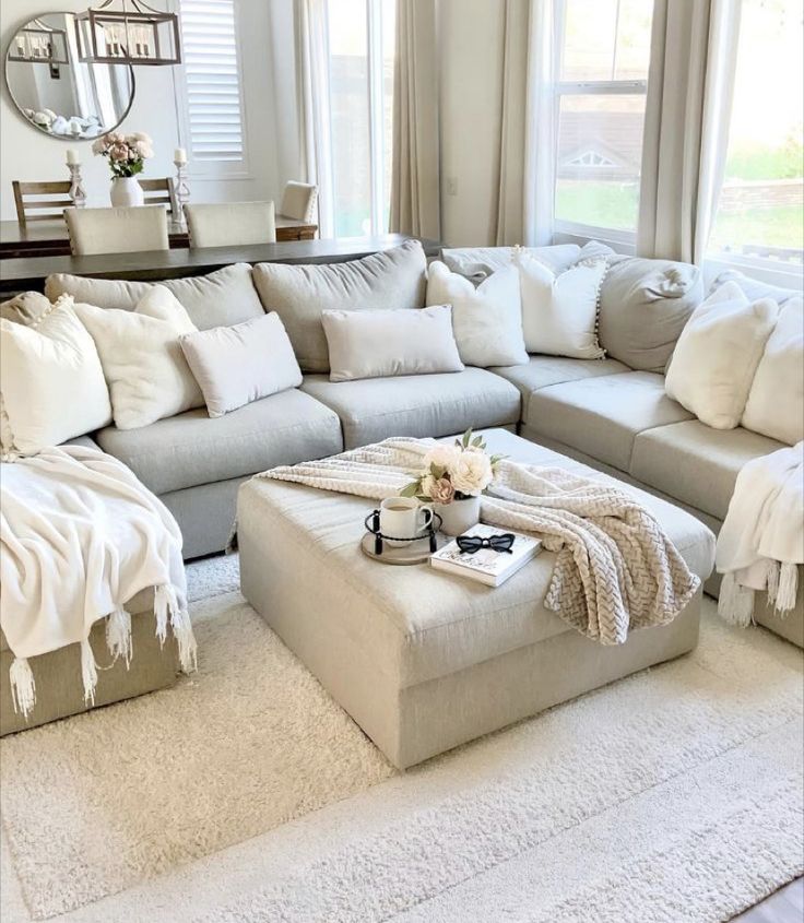 a living room filled with lots of white furniture and pillows on top of a rug