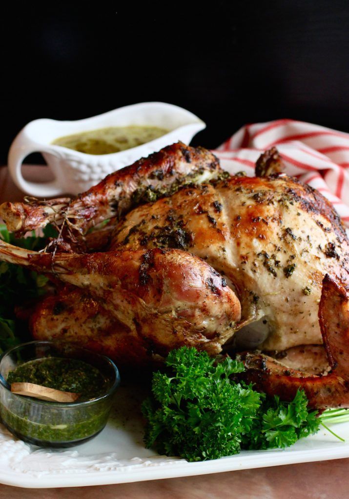 a roasted turkey on a platter with parsley garnish and dipping sauce