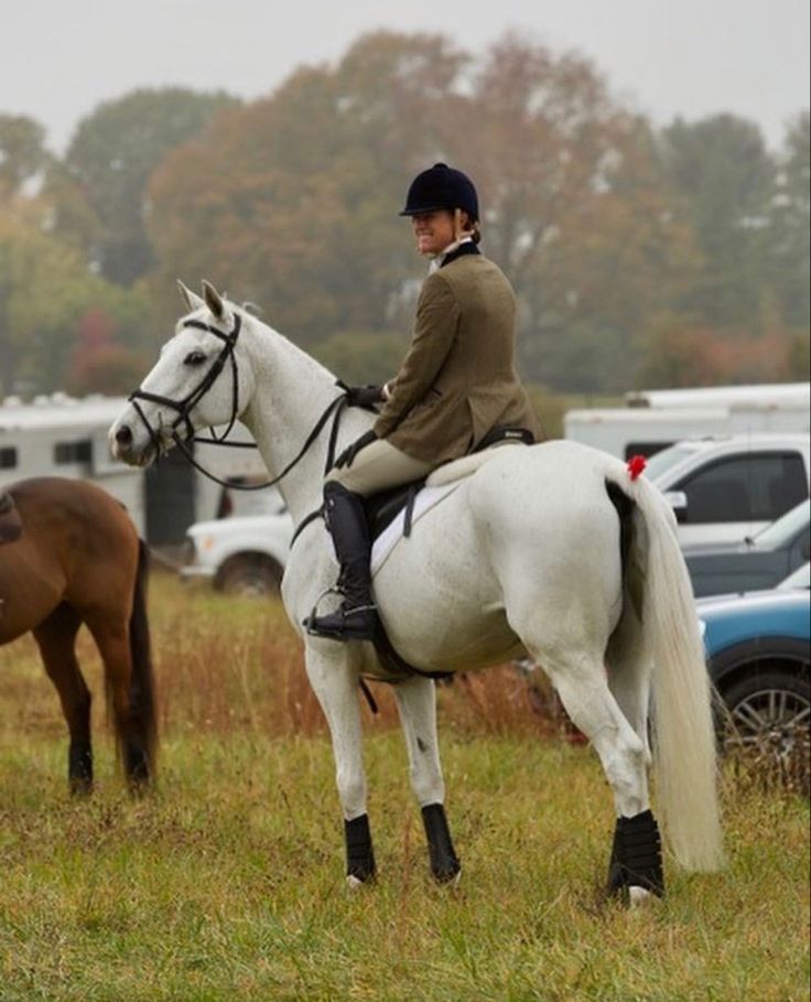 a woman riding on the back of a white horse next to a brown and black horse