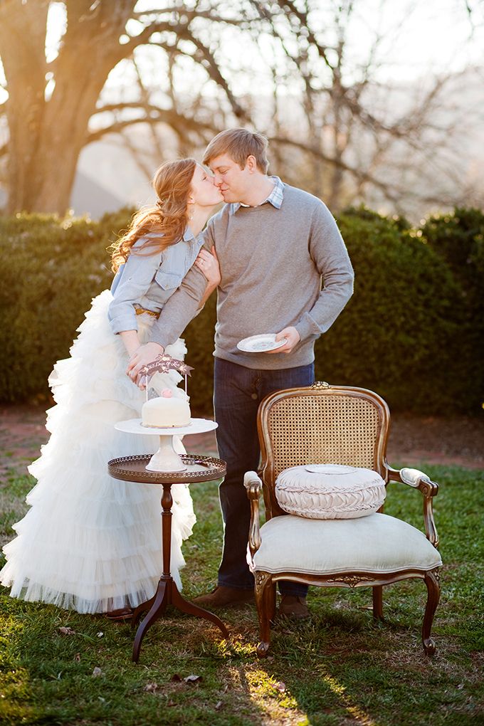 a man and woman standing next to each other in front of a table with a cake on it