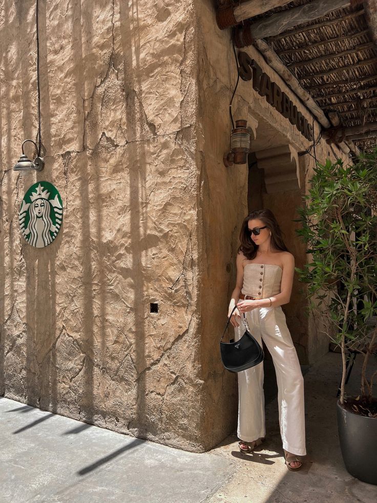 a woman standing in front of a building with a starbucks sign on it's side