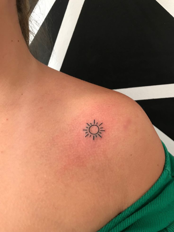 a woman with a small sun tattoo on her shoulder