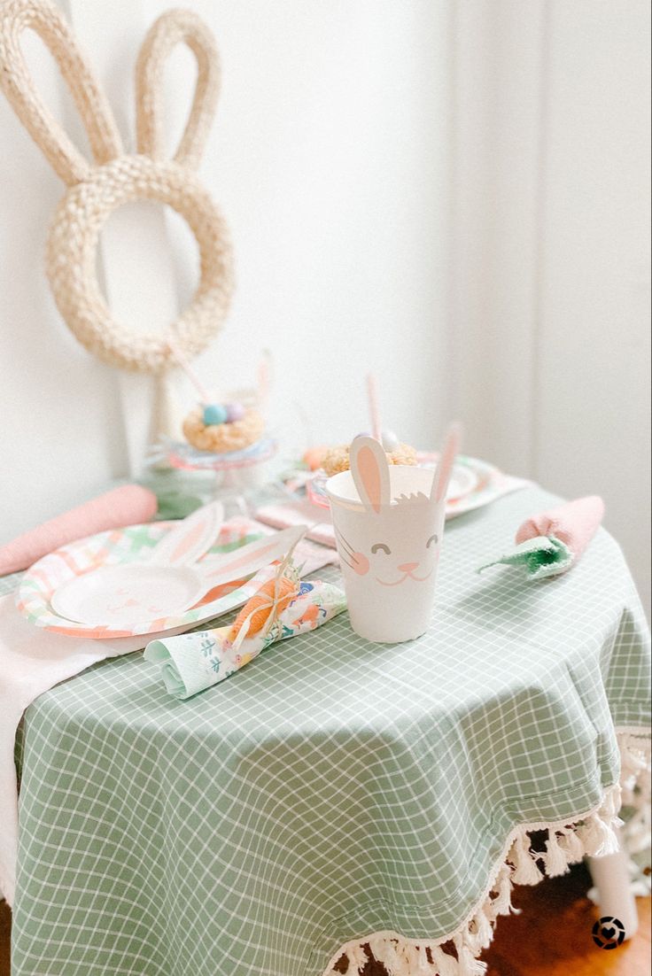 the table is set with plates, cups and bunny ears on it's head