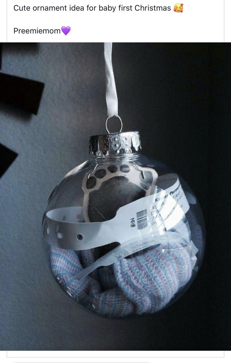 a glass ornament with a baby's foot in it hanging on a wall