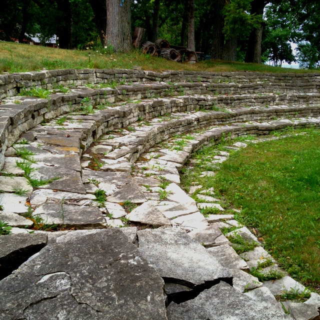 an outdoor seating area with stone steps and grass growing on the ground next to it