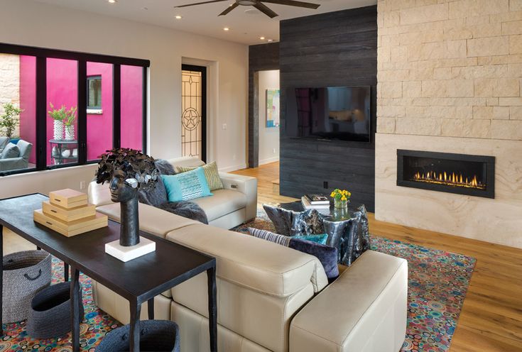 a living room filled with furniture and a flat screen tv mounted to a wall above a fireplace