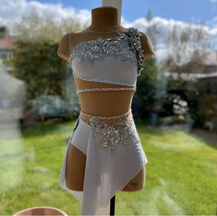 a mannequin dressed in white with silver sequins on it's chest