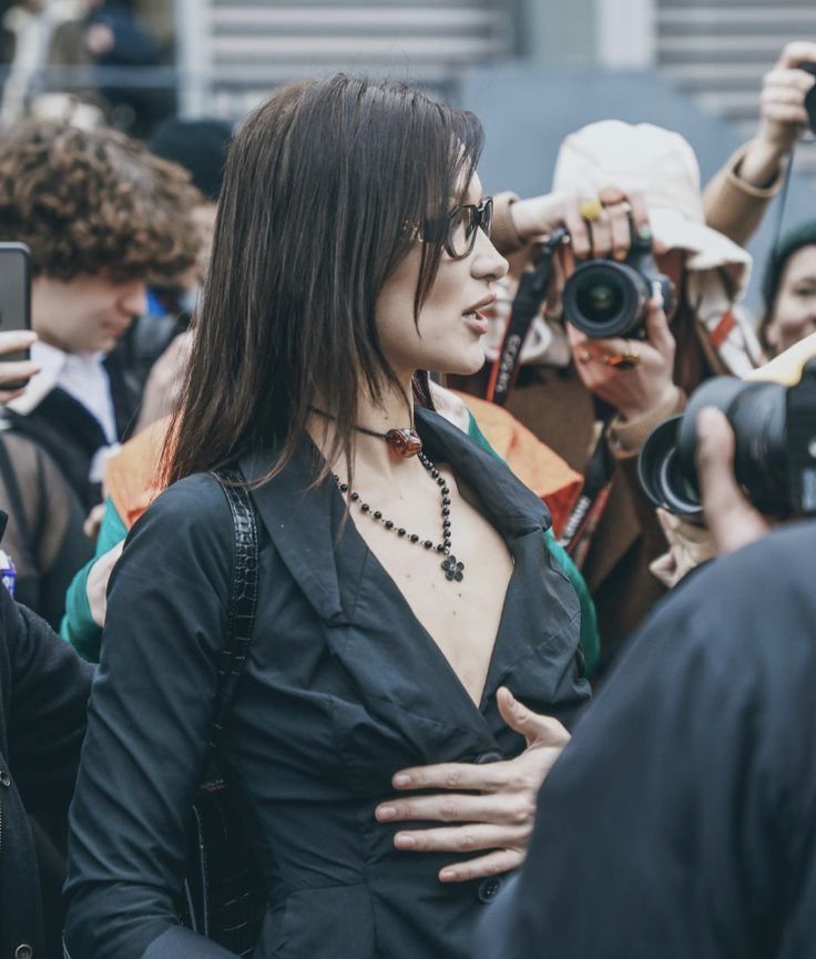 a woman is standing in front of a group of people taking pictures with her cell phone