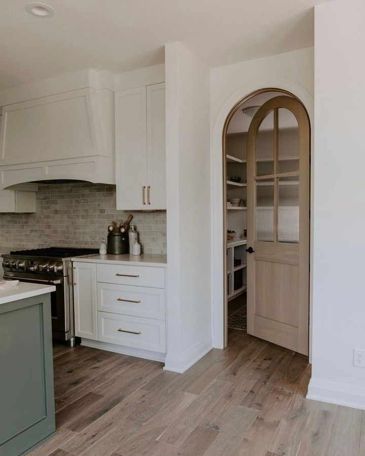 a kitchen with white cabinets and wood floors