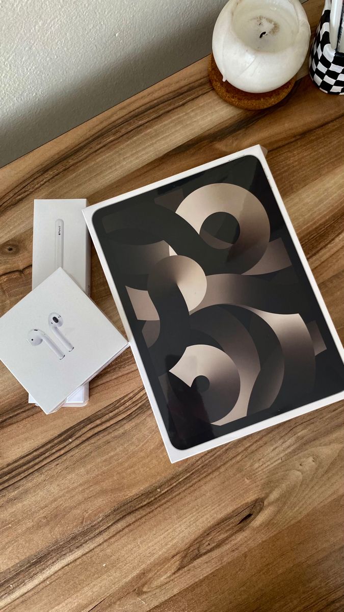 an apple computer sitting on top of a wooden table next to a white box and other items